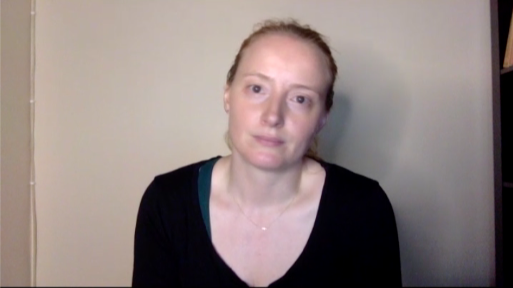 Close up of a woman looking into the camera in front of a white wall