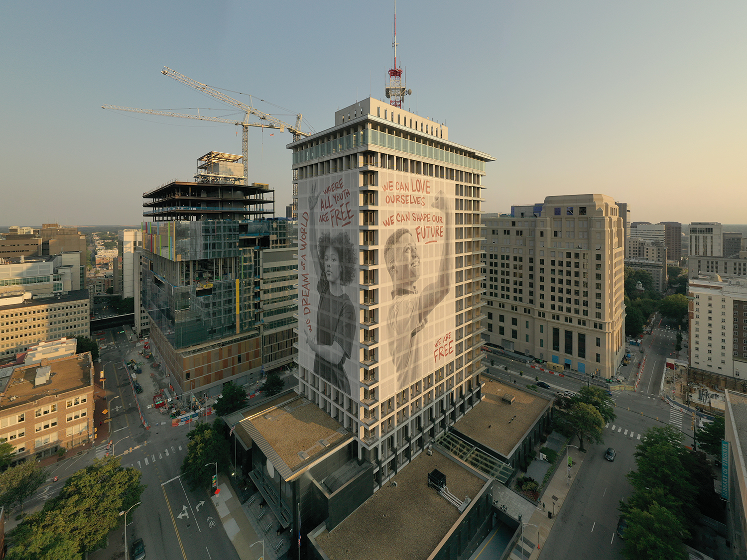 Large-scale public mural of two people posing next to words of affirmation, displayed on two sides of the building