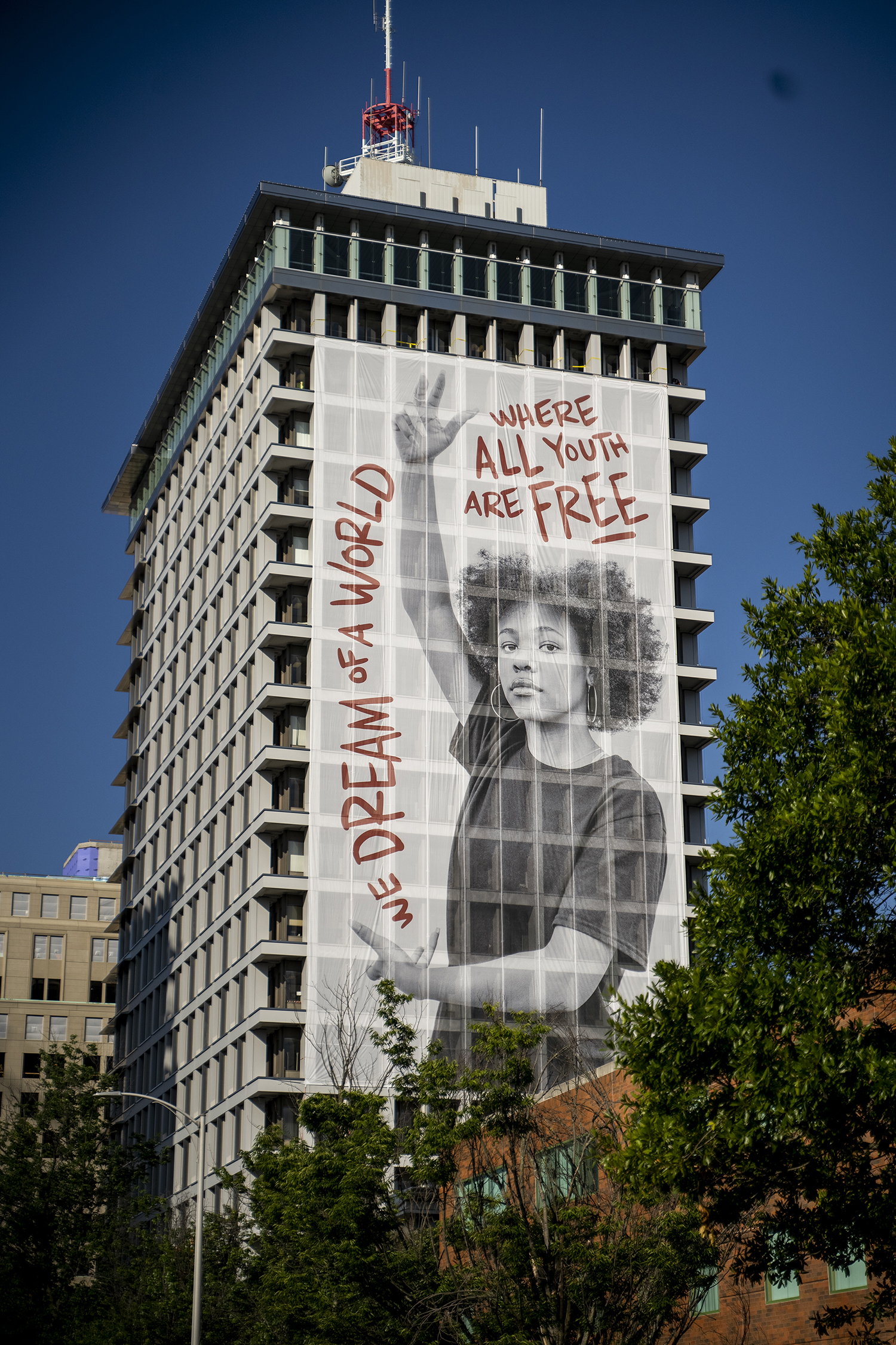 Photo of girl posing on a large scale public mural; beside her is bolded text that reads,