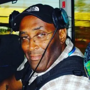 Larry Edgeworth turned, facing the camera and wearing audio equipment