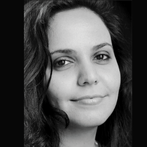 Black and white close-up portrait of a woman with long, dark hair, looking at the camera with a gentle expression and a slight smile.