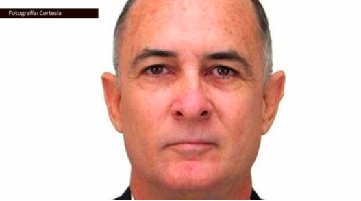 A middle-aged man with short dark hair and fair skin is shown in a close-up portrait against a plain white background.