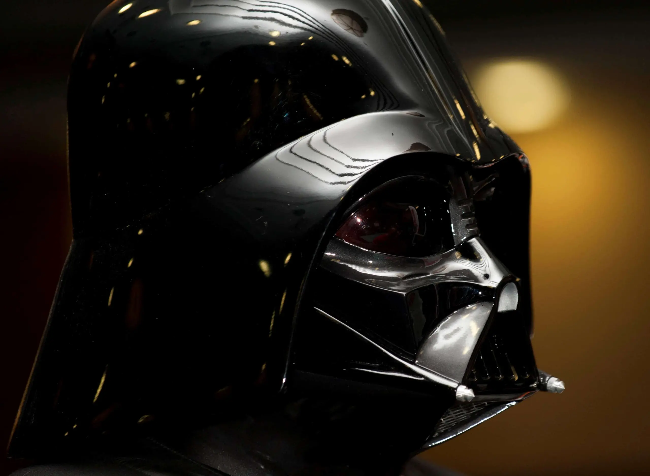 A close-up of a shiny black Darth Vader helmet from Star Wars, its reflective surface and intricate mask details evoking the intensity of prison writing, set against a blurred, dark background.