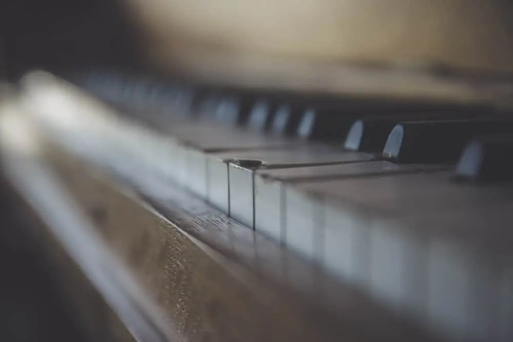 Close-up of piano keys with a shallow depth of field, focusing on the white and black keys, while the background and edges gradually blur. The image captures the texture and details of the keys.