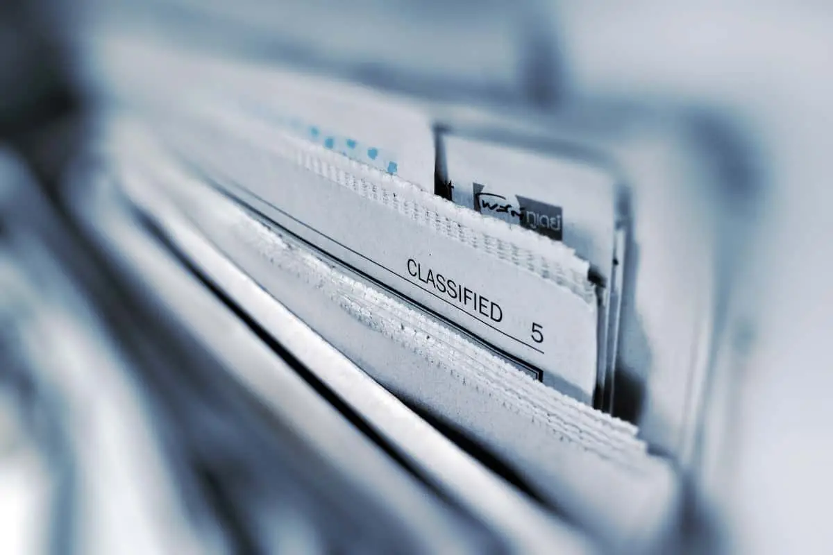 A close-up of a stack of documents, with one paper labeled CLASSIFIED and the number 5 visible, suggesting confidential or sensitive information. The image is focused on the label, with blurred surrounding papers.