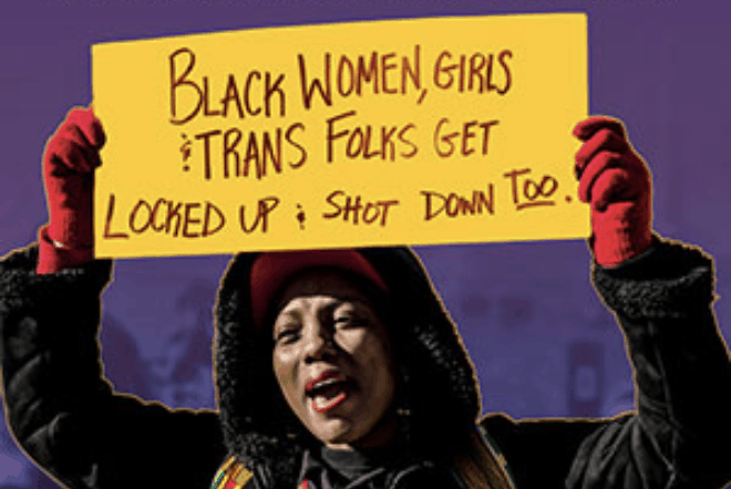 A person wearing red gloves and a winter coat holds a yellow sign that reads, Black women, girls & trans folks get locked up & shot down too. The background is purple.