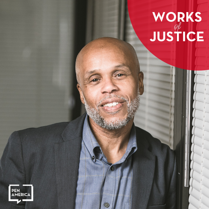 A man with a shaved head and beard, wearing a blazer and button-up shirt, smiles while leaning against a wall. The image features Works of Justice and Pen America logos in the corners.