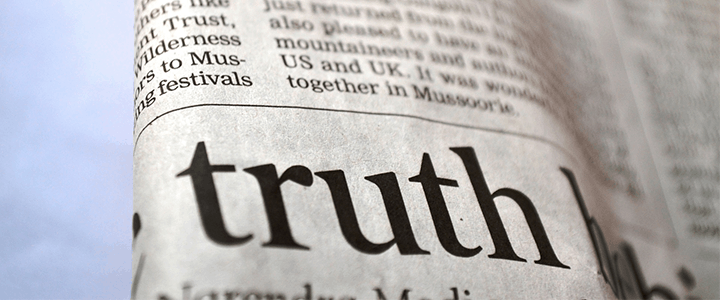 A close-up of a newspaper page with the large, bold word truth prominently visible in the center, surrounded by other smaller, blurry text—including mentions of coronavirus.