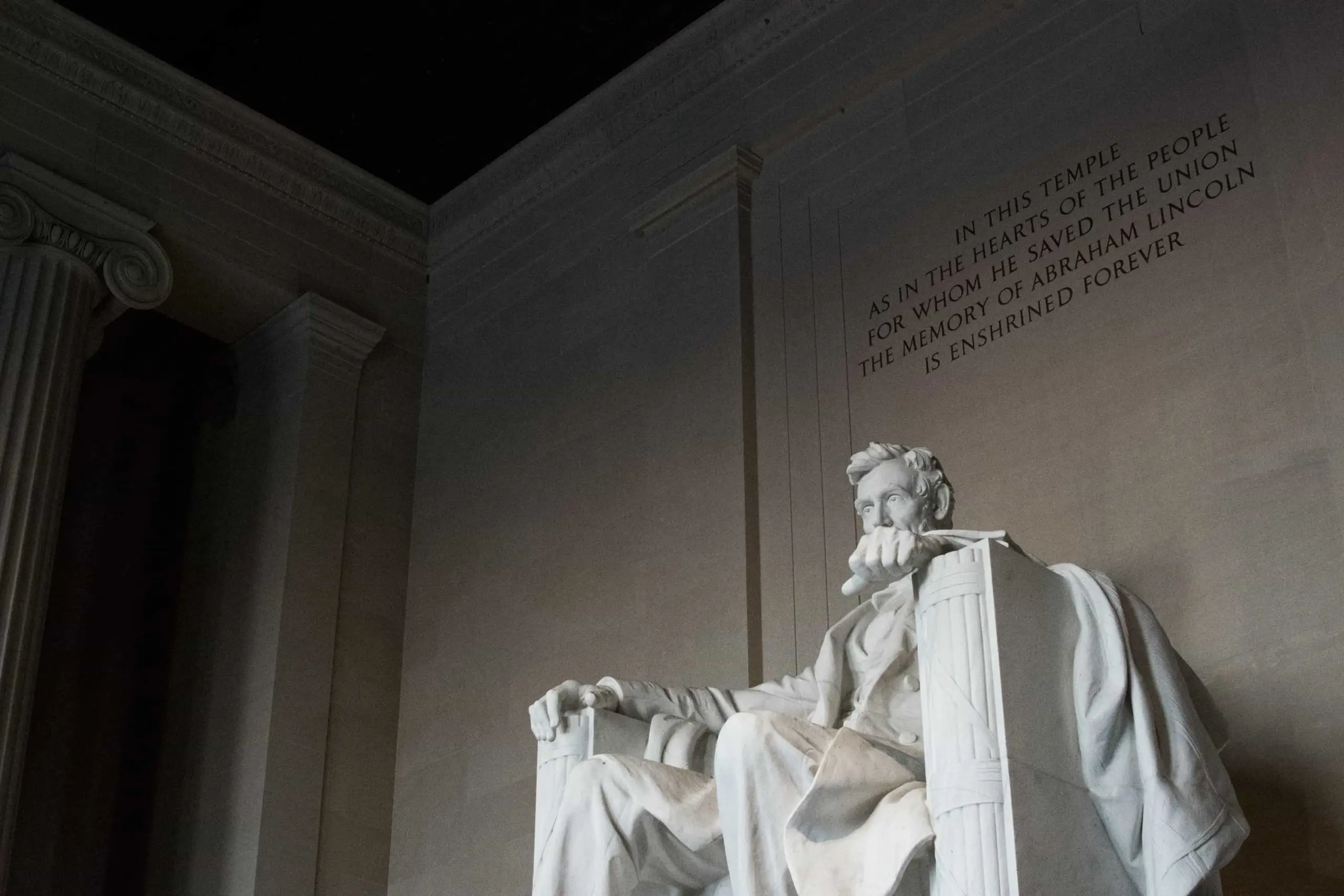 A low-angle view of the Abraham Lincoln statue at the Lincoln Memorial in Washington, D.C., with part of the engraved dedication visible on the wall behind—a powerful symbol, especially when reflecting on Juneteenth and its significance.