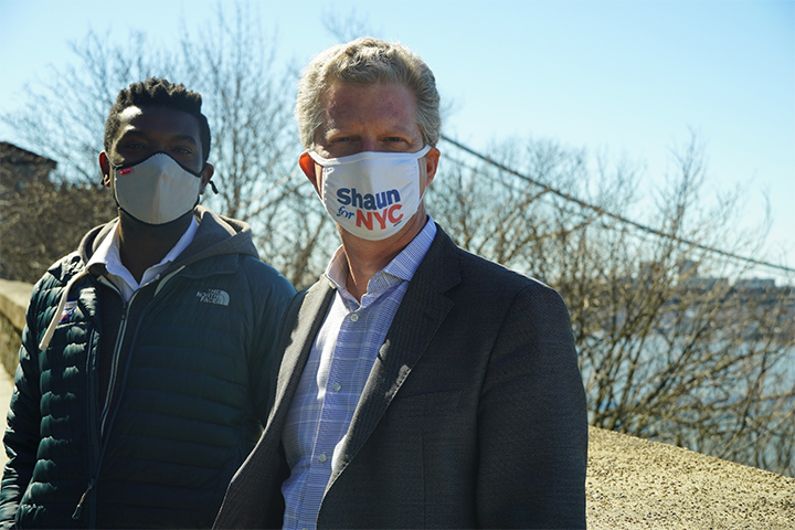 Shaun Donovan standing, looking at the camera next to another person