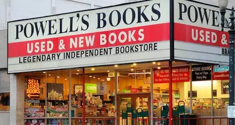 Storefront of Powell’s Books, displaying a large sign that reads “Powell’s Books Used & New Books” with the subtitle “Legendary Independent Bookstore.” The windows reveal bookshelves and displays inside.
