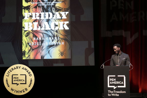 A man stands at a podium labeled PEN America on a stage, smiling. Behind him, a screen displays the book cover for Friday Black by Nana Kwame Adjei-Brenyah. A gold PEN America Literary Award Winner badge is in the corner.