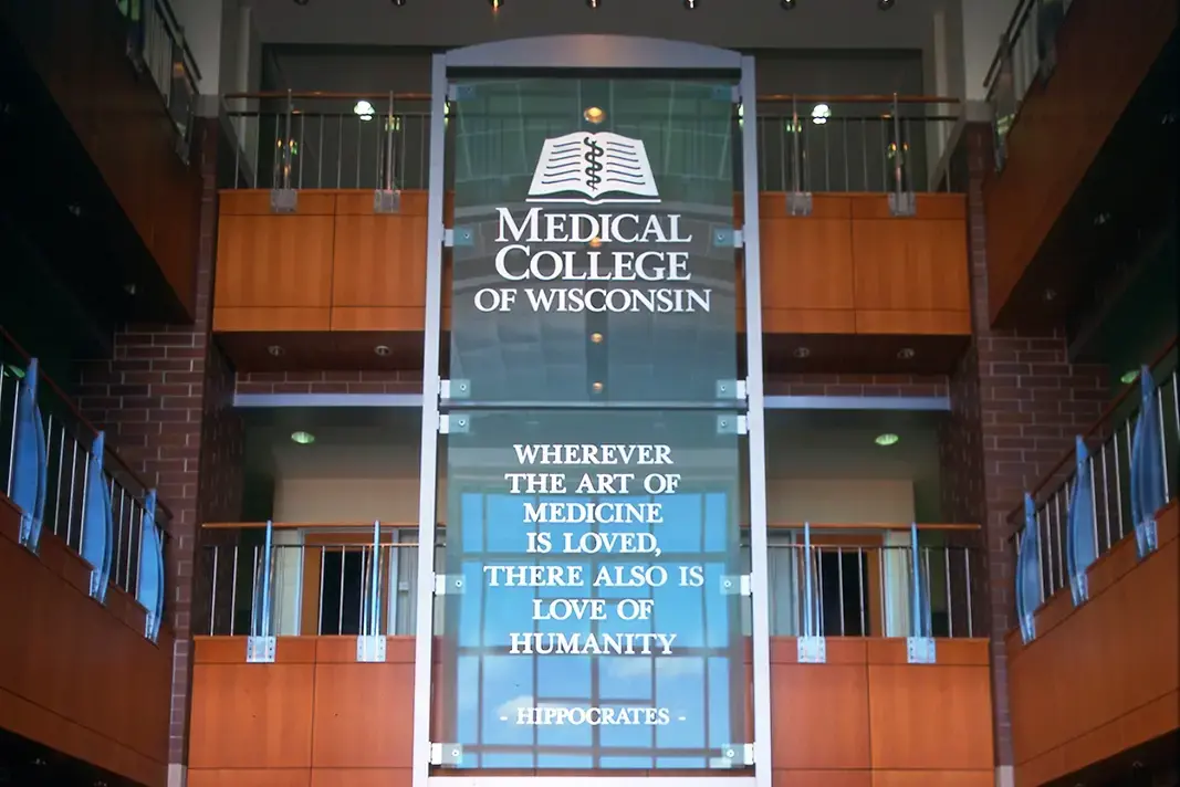 A large glass panel at the Medical College of Wisconsin displays a quote by Hippocrates: Wherever the art of medicine is loved, there also is love of humanity, set in a modern building with wood and glass accents.