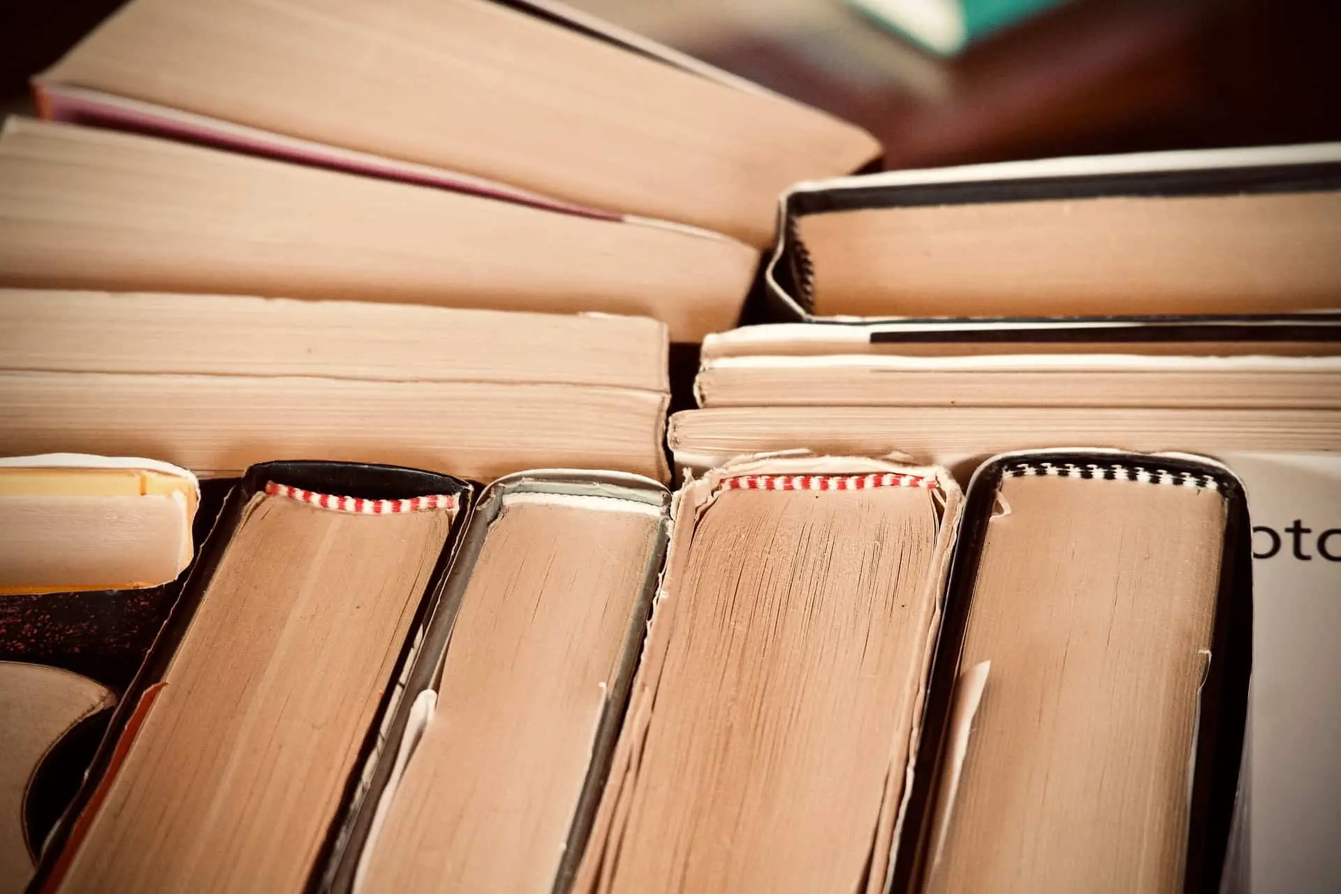 Close-up view of several books arranged with their pages and spines visible, showing a variety of colored bookmarks and worn edges, suggesting frequent use or study.