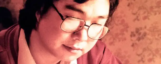 A person with glasses and short dark hair is looking down thoughtfully, perhaps reflecting on censorship in China. The background is softly lit with a warm tone and a floral-patterned wallpaper.