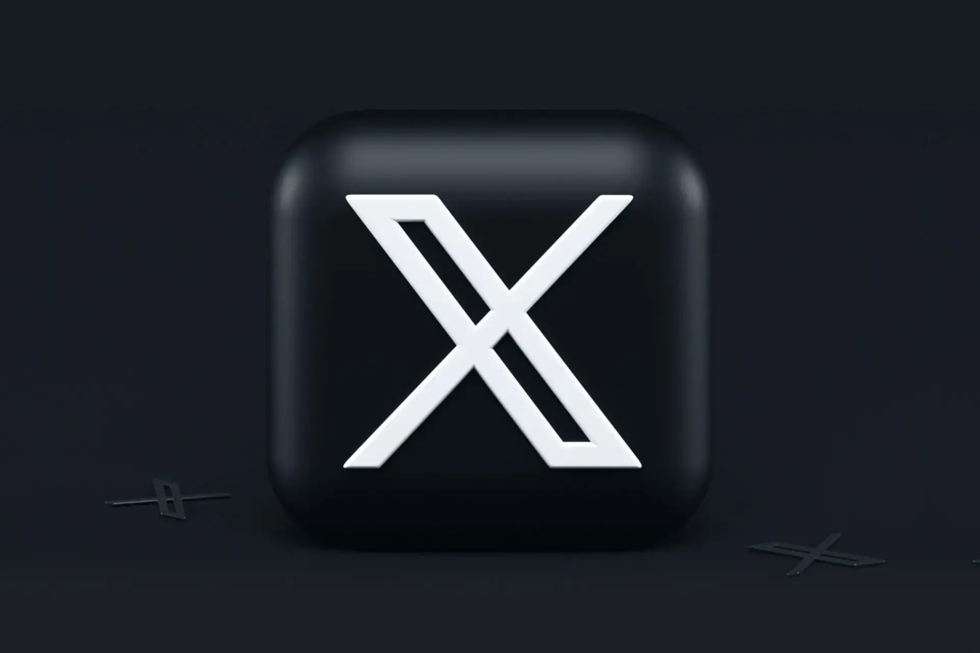 A black square with rounded corners displays a bold white X in the center, set against a dark background with small, subtle X shapes in the corners.