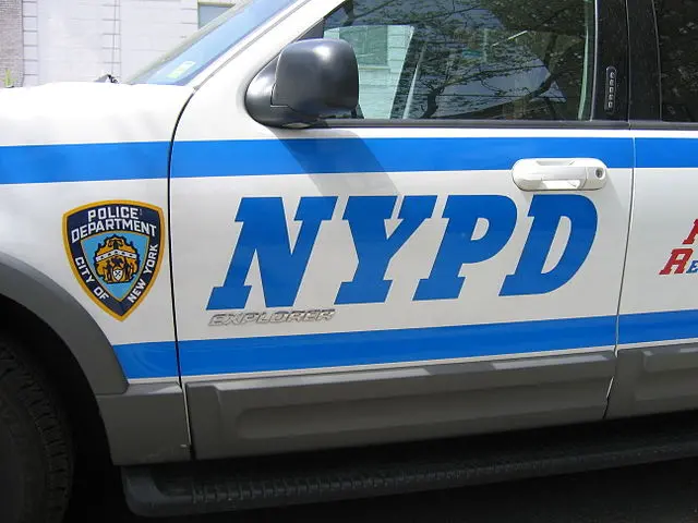Close-up of a New York Police Department (NYPD) vehicle door, showing the NYPD logo in large blue letters and the police department badge decal.