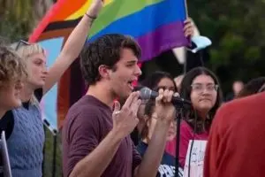A man singing into a microphone with a crowd of people.