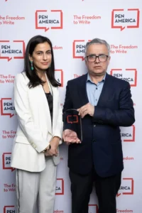 A man and woman holding an award, celebrating as Narges Mohammadi is awarded the Nobel Peace Prize.