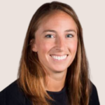 A woman with long, straight, light brown hair smiles at the camera. Wearing a black top, she stands against a plain light background—her thoughtful expression hints at her views on book bans 2023.