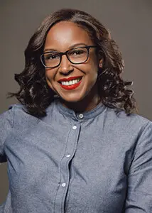 A woman wearing glasses and smiling.