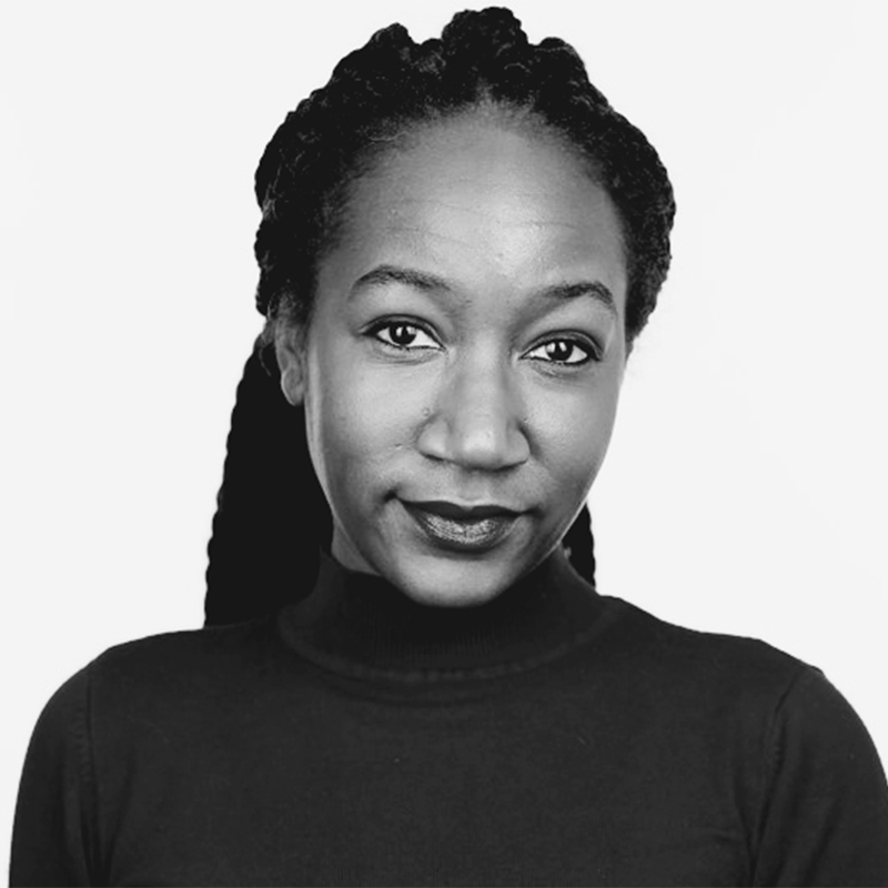 Black and white portrait of a woman with braided hair, wearing a high-neck dark top, looking directly at the camera with a neutral expression against a plain background.