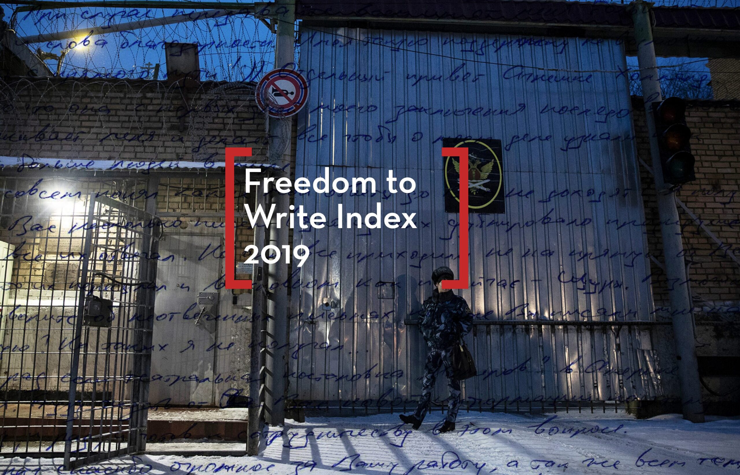 A person stands outside a gated, barbed wire-topped building at dusk, snow covering the ground. Overlaid handwritten text, red brackets, and Freedom to Write Index 2019 highlight the ongoing struggle for creative expression.
