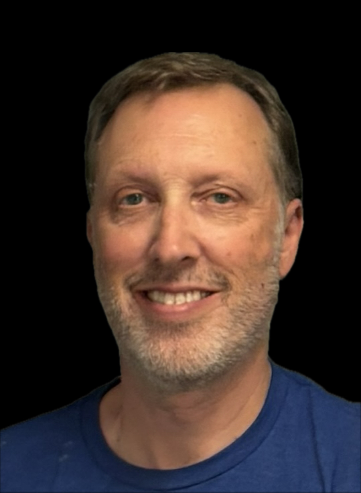 A middle-aged man with short light brown hair, a trimmed beard, and blue eyes, smiling and wearing a blue shirt. The background is solid black.
