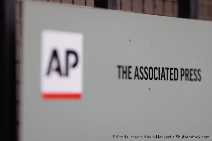 A sign displaying the Associated Press (AP) logo and the words THE ASSOCIATED PRESS on a wall. Editorial credit: Kevin Hackert / Shutterstock.com.