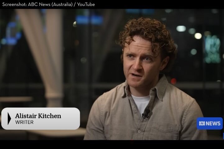 A man with curly hair, wearing a beige jacket over a white shirt, is speaking in an interview. A chyron identifies him as Alistair Kitchen, Writer. The ABC News logo appears in the corner.