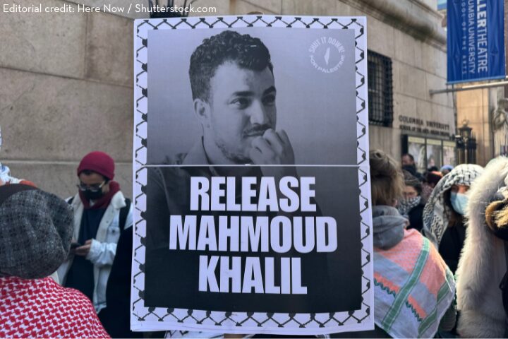 A protester holds a sign with a black-and-white photo of Mahmoud Khalil and the words RELEASE MAHMOUD KHALIL at a crowded outdoor demonstration.