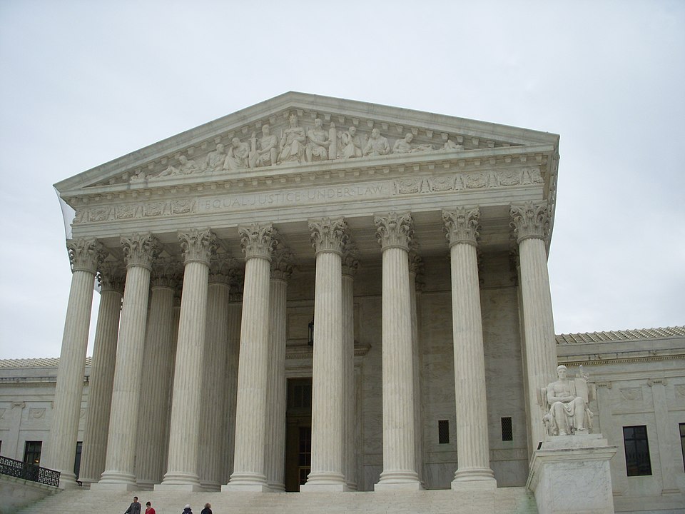 The image shows the front facade of the United States Supreme Court building, featuring large columns, detailed carvings, and the inscription EQUAL JUSTICE UNDER LAW above the entrance.