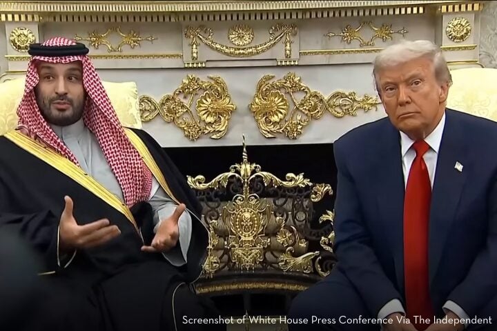 Two men sit side by side in an ornate room with gold decorations. One wears traditional Saudi attire and gestures while speaking; the other, known for Trump attacks journalists, wears a dark suit and red tie, looking forward with a neutral expression.