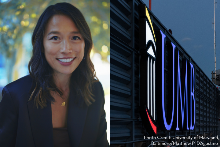 A woman with long brown hair smiles at the camera on the left; on the right, a large illuminated “UMB” sign is shown on the side of a building. Photo credit: University of Maryland, Baltimore/Matthew P. D’Agostino.