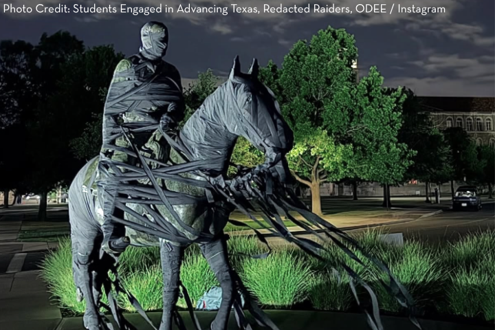 A statue of a person on a horse is wrapped entirely in black fabric strips at night, obscuring most details—a striking sight on the Texas campus, sparking conversations about censorship. Trees and a building are visible under artificial lighting.